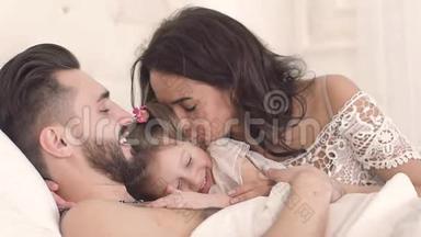 <strong>一家人</strong>在床上微笑，年轻的母亲亲吻着她的小<strong>女儿</strong>