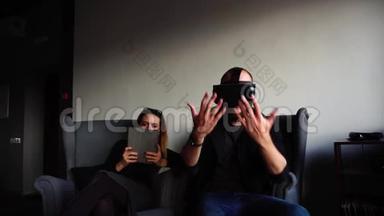 男人和女孩朋友带着小<strong>玩</strong>意，男人戴着<strong>VR</strong>眼镜，坐在现代咖啡馆的扶手椅上，下午聊天。