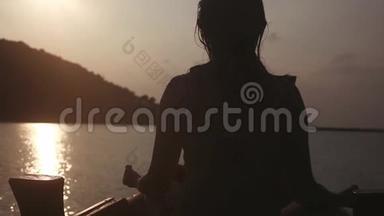 女孩冥想坐在船上的洛托斯的姿态在海上，而度假在惊人的日落。 1920x1080