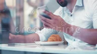 一个年轻的棕色头发的男孩坐在咖啡馆里©靠窗喝咖啡，电话响了，他拿起了