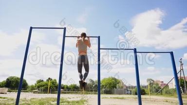 年轻的运动健身妇女在户外健身房锻炼，日出时做引体向上运动