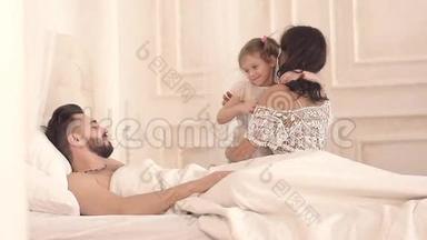 幸福的三口之家：母亲、父亲和女儿在床上玩
