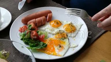 吃早餐的人。 刀叉在手.. 美式早餐，包括煎鸡蛋、香肠、沙拉和烤面包。