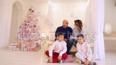 <strong>双胞胎兄弟</strong>保密，带着娇惯的目光看着父母，坐在卧室的地板上过圣诞节