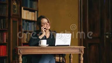 一个年轻漂亮的女学生在<strong>室内图</strong>书馆学习时用手机说话