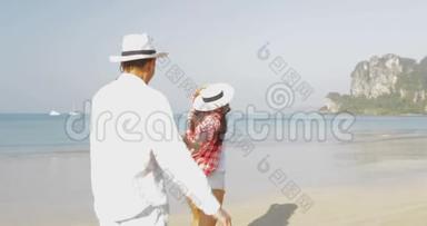 女人牵着男人的双手在沙滩上奔跑，年轻的快乐游客在度假