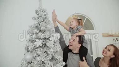 一家人站在圣诞树附近，一边笑着说着，一边摸着玩具，一边等待圣诞节..