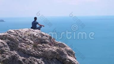 人在边上沉思，坐在岩石的顶部，背景是蓝色的大海和天空，鸟儿在缓慢地飞翔