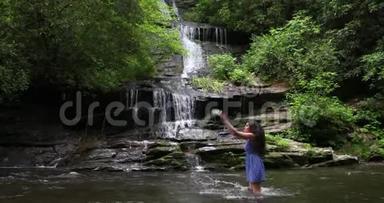 美丽的女士在瀑布旁泼水