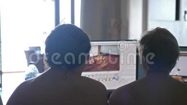<strong>背面</strong>的两个年轻男子朋友裸胸在家分享信息和使用<strong>电脑</strong>。 工作