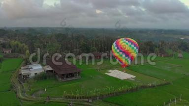 空中拍摄的一个热气球，正飞过绿色的大稻田。 旅行到巴厘岛的概念。
