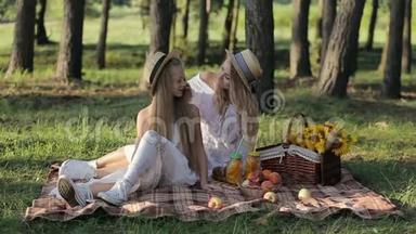 一位快乐的母亲和幸运的女儿一起坐在城市公园里玩，在日落的温暖的夜晚野餐