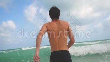 英俊的年轻人走进大海，缓慢地拍打着波浪。 <strong>快乐暑假</strong>休息放松娱乐