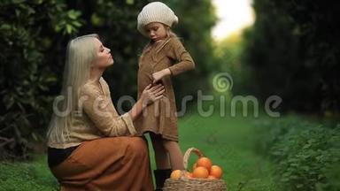 在绿色的阳光果园里，带着一篮子水果的绿色草地上，带着小女孩的慈爱的母亲的侧面景色，全高清
