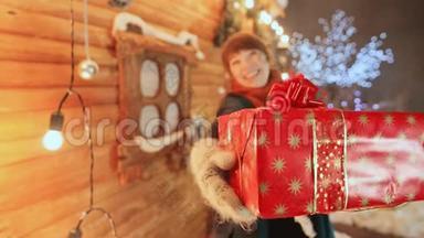 这个女孩在木制童话屋的背景下，滑稽和开玩笑地给观众一份礼物。 圣诞节和新