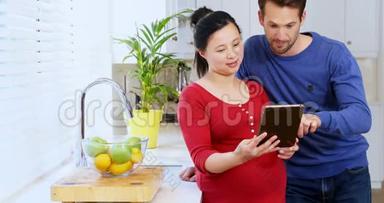 使用<strong>数码</strong>平板电脑的孕妇夫妇在<strong>家</strong>厨房4k