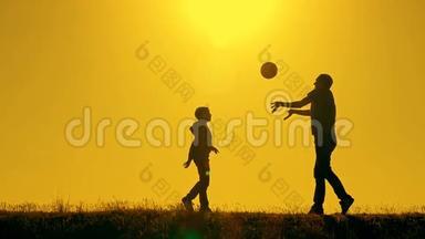 日落时分，父亲和儿子在公园里打排球，在灿烂的阳光下剪影