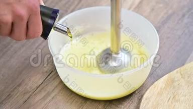 在塑料碗里用<strong>搅拌</strong>器将自制蛋黄酱的混合物<strong>搅拌</strong>。 橄榄油