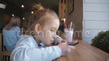 可爱的小女孩在咖啡馆里用智能手机。 快乐的孩子在<strong>放学</strong>后玩得开心和放松。 自然室内