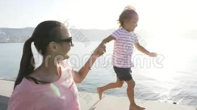 年轻的母亲和小女儿牵着手跑着，笑着笑着