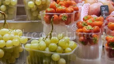 市场上新鲜的葡萄、草莓和热带水果架