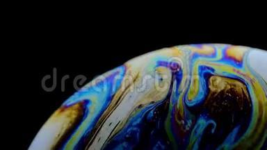 一个肥皂泡的五彩彩虹颜色看起来像一个在黑色背景下孤立的梦幻星球