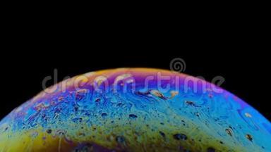一个肥皂泡的五彩彩虹颜色看起来像一个在黑色背景下孤立的<strong>梦幻星球</strong>