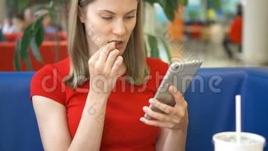 女人坐在咖啡馆里，用她的智能手机和朋友聊天吃炸薯条
