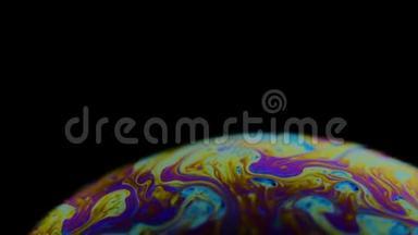 一个肥皂泡的五彩彩虹颜色看起来像一个在黑色背景下孤立的梦幻星球