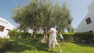 绿色花园里有一棵大橄榄树的快乐父母和孩子