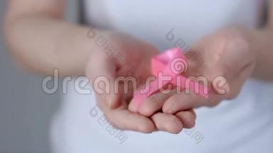 女士双手捧着粉红色乳腺癌意识丝带-乳腺癌意识概念