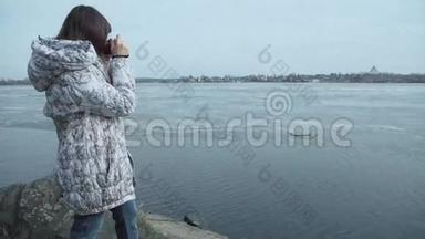 一位女士正在池塘旁边的老式复古风格相机上拍摄。