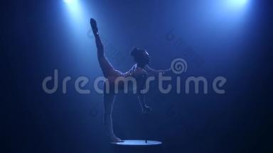 体操运动员在演播室的桌子上表演魔术。 烟雾蓝色背景。 慢动作