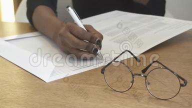 接待处的女孩正在<strong>填写</strong>表格中的<strong>信息</strong>。 非洲手的特写镜头。 眼镜