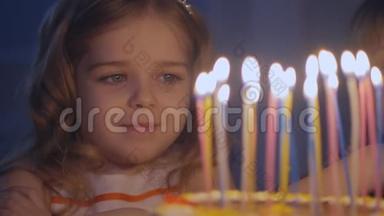 一个快乐的小女孩看着节日蛋糕上的蜡烛，慢慢地许愿
