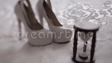 由白色<strong>高跟鞋</strong>后面的老式沙漏组成的婚礼构图的特写。