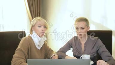 两个女<strong>人坐</strong>在笔记本<strong>电脑前</strong>的办公室里说话