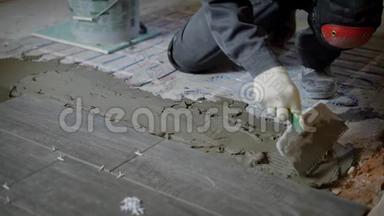 <strong>修理</strong>工<strong>正在</strong>地板上抹建筑砂浆，用抹刀与牙齿对齐，准备安装瓷砖