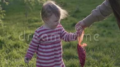 快乐的蹒跚学步的女孩<strong>走</strong>在草地上，在春天的公园里从母亲那里拿<strong>走</strong>了一颗红色的复古<strong>心</strong>。