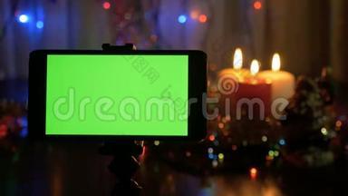带有绿色屏幕的智能手机。 新年背景模糊。 一个很好的机会来添加你的问候视频。