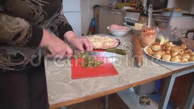 女人`手把腌制好的黄瓜切成薄片，准备披萨。