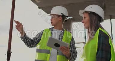 在脚手架施工计划或施工计划上讨论的团队或建筑师、建筑工人或戴头盔的工人