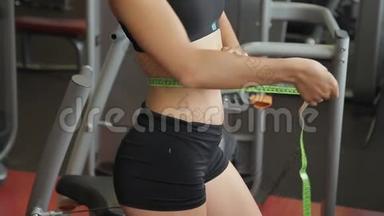 女<strong>运动</strong>员在<strong>室内运动</strong>俱乐部用丝带测量腰部。