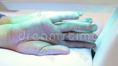 银屑病患者的手在紫外线灯下特写。