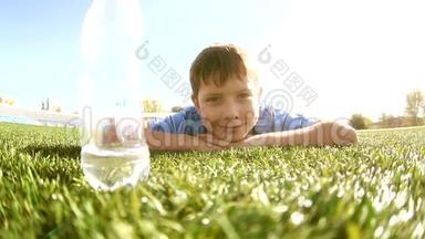 小男孩足球运动员在训练期间从塑料瓶里喝水。 青少年踢足球