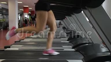 女足穿着<strong>跑鞋</strong>沿着跑步机在<strong>健身</strong>房跑步。