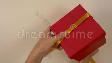快速运动时间流逝。 包装红色礼盒.. 白人男子的手包装礼品盒。 男人的双手系着丝带