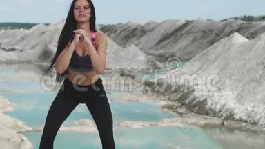 穿着黑色运动服的运动型黑发女孩在一个白色粉笔采石场和蓝色的水对抗。<strong>蹲下</strong>