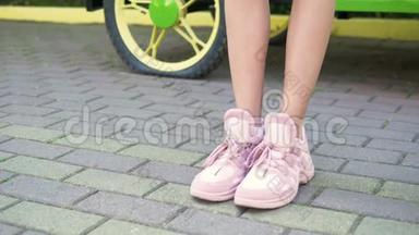 特写镜头。 女腿穿着时尚的粉红色运动鞋。 带着人行道走在街上的女孩。 自然阳光充足