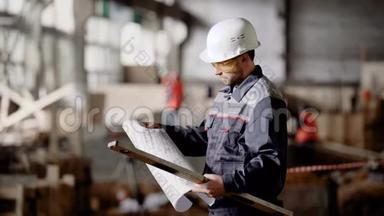 男工程师在防护硬帽站在建筑现场持施工方案和<strong>精神</strong>水平。 检查员